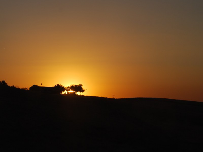 The sun sets behind a rural home in California's San Joaquin Valley.
